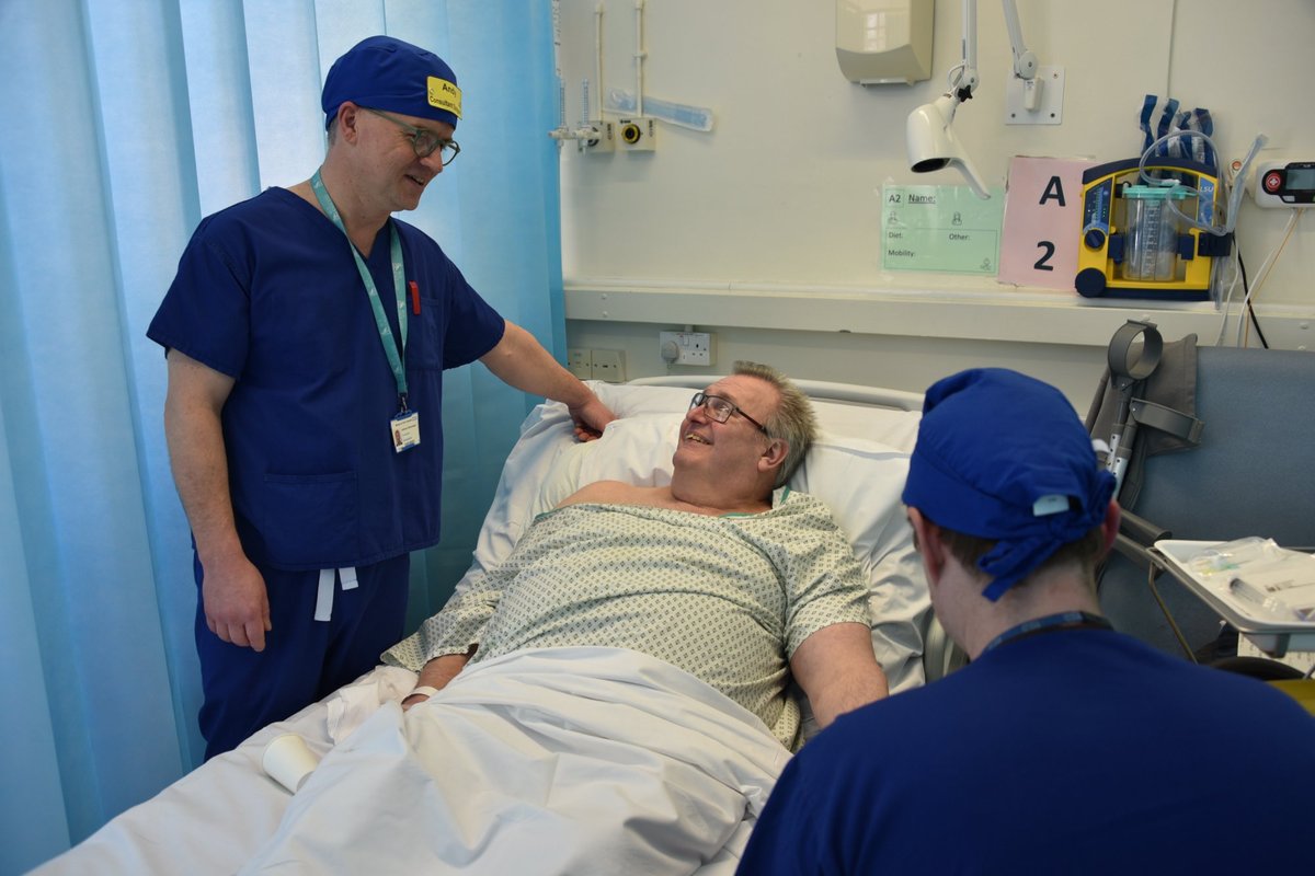 Clinician wearing a Theatre Badge Hat greeting a patient at the bedside